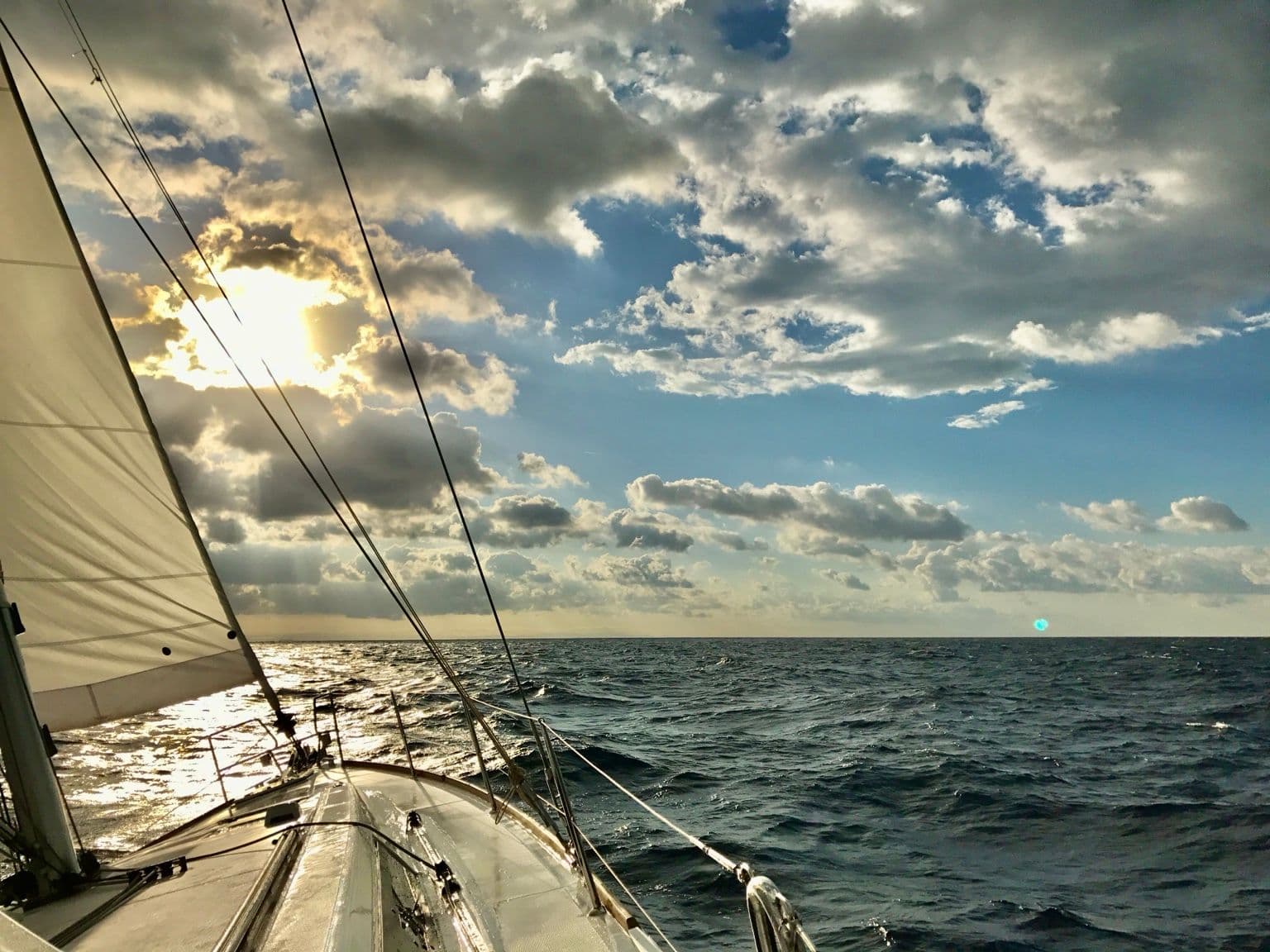 Vela e prua verso il sole, tra le nuvole